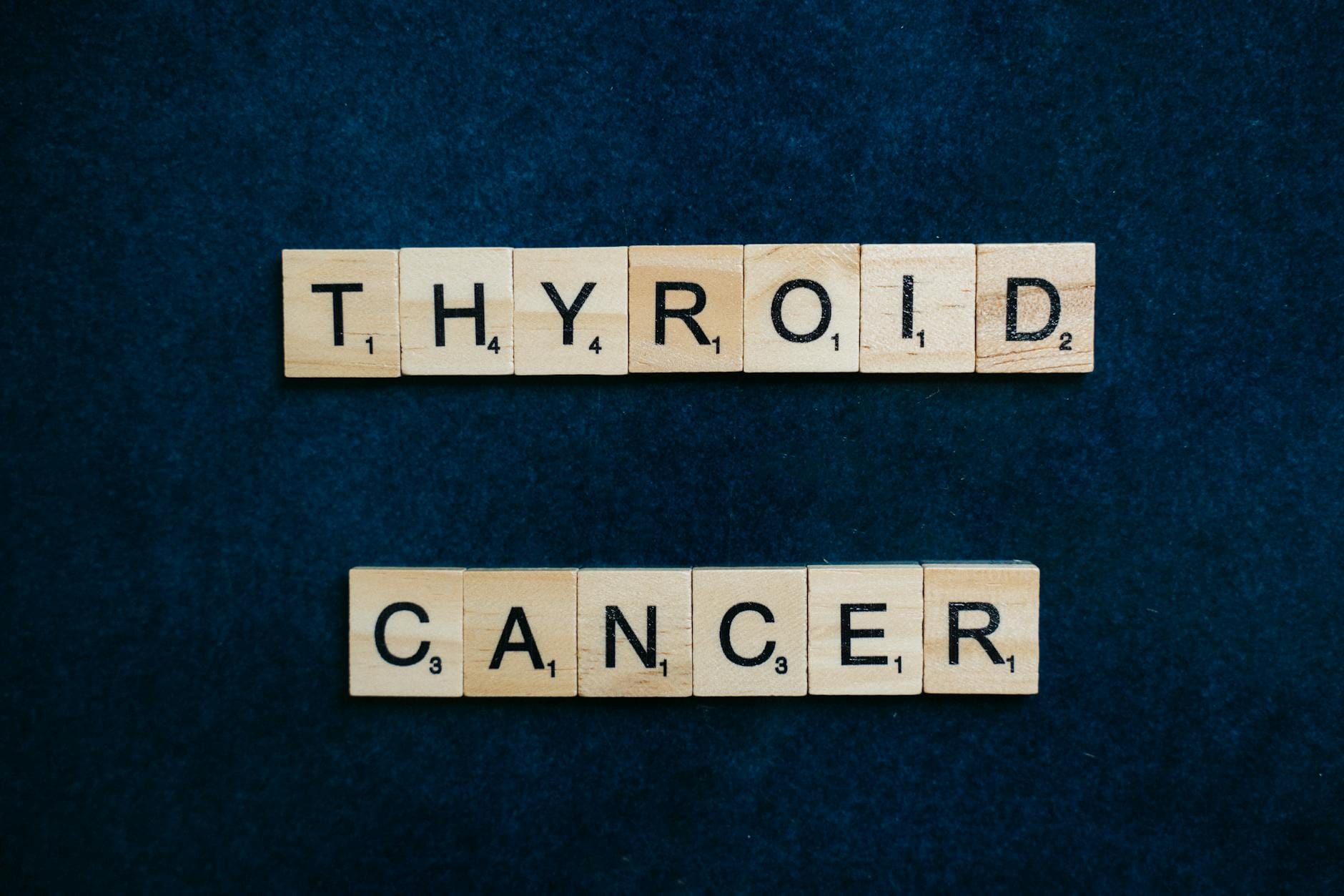 Napis Thyroid Cancer z klocków scrabble na ciemnoniebieskim tle