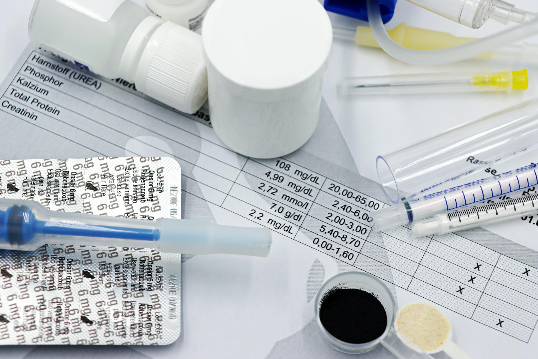 Strzykawki i leki leżące na wynikach badań krwi