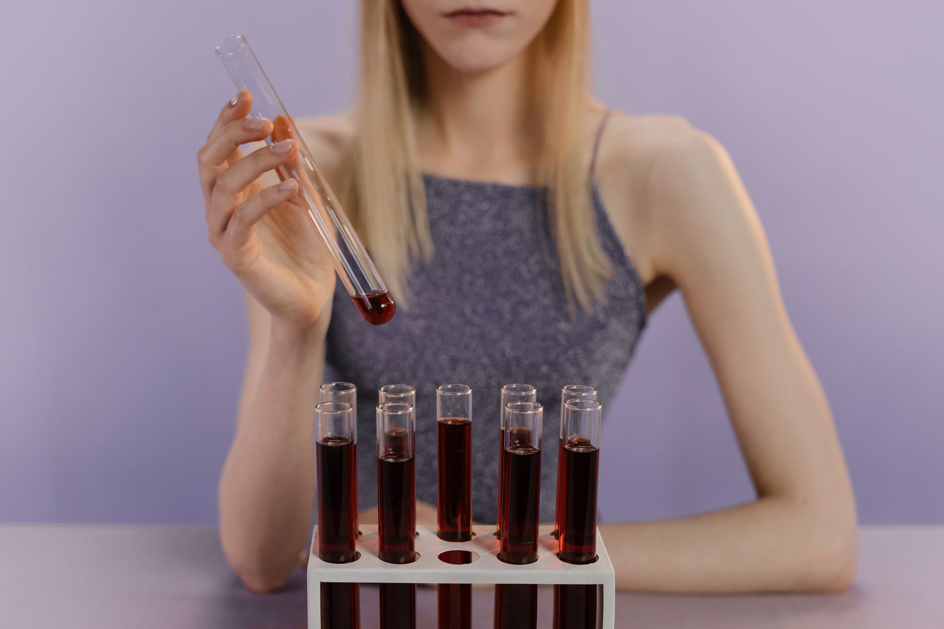 Kobieta w laboratorium analizuje czerwone próbki krwi w probówkach