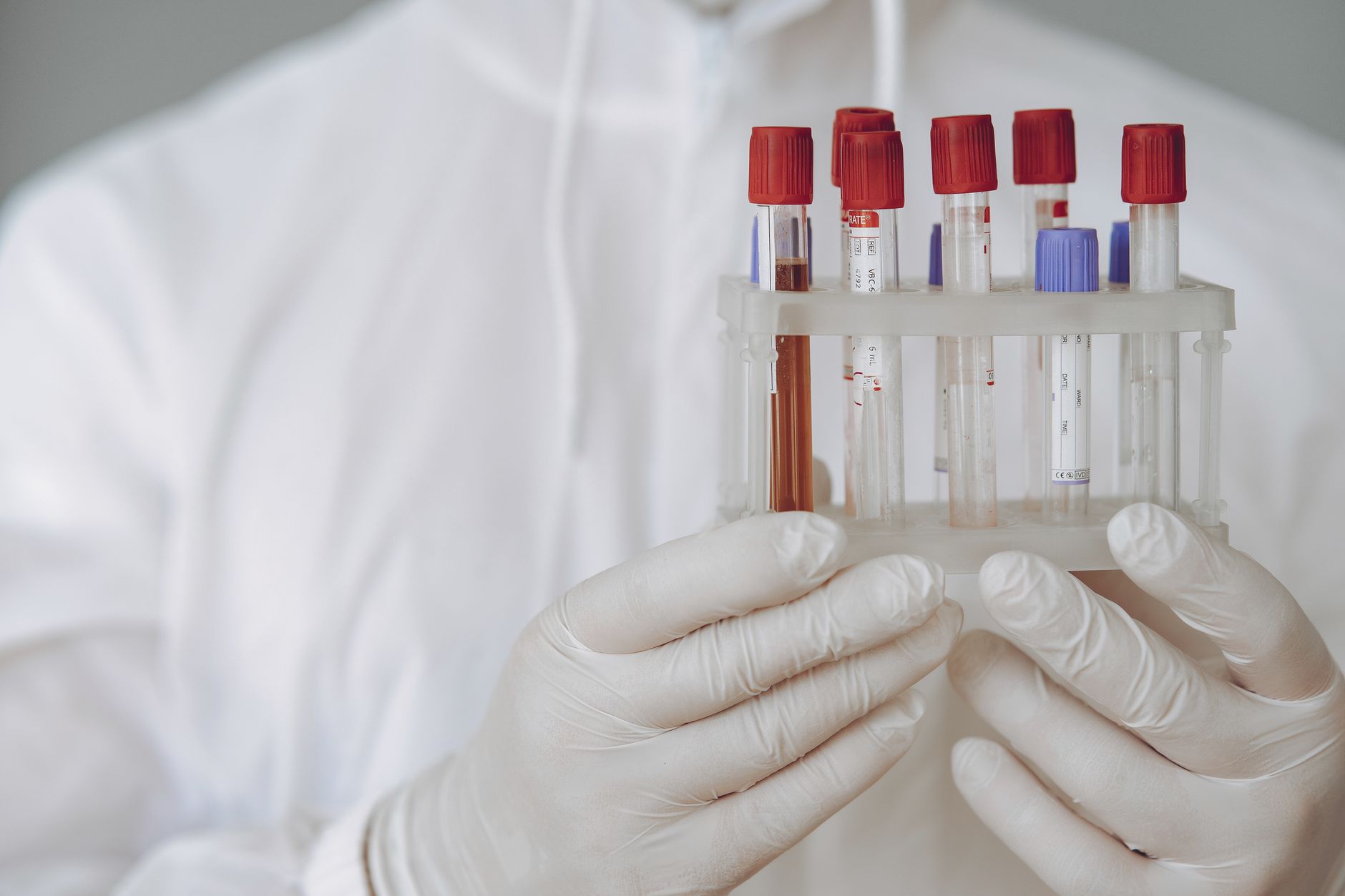 Naukowiec w ochronnym stroju analizuje probówki z krwią w laboratorium